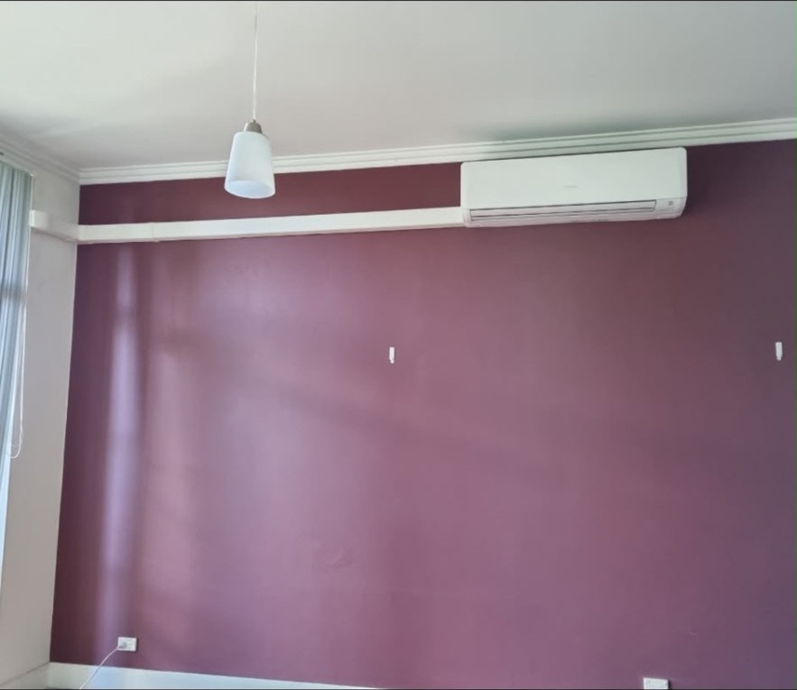 Wall-mounted split system air conditioner installed above a plum feature wall